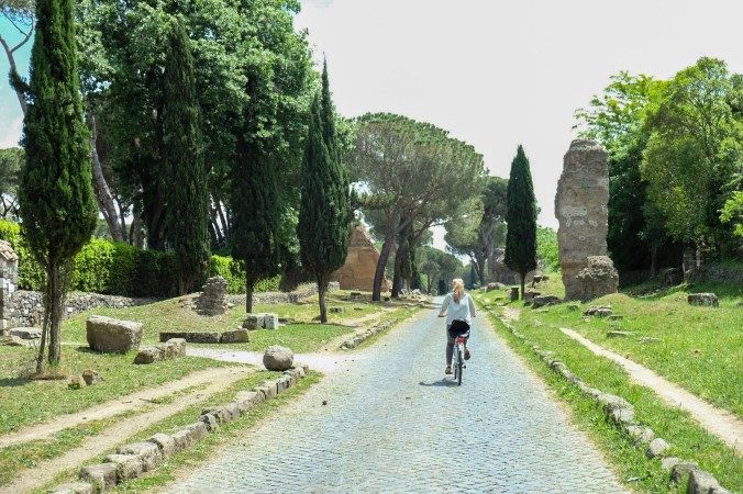 Biking along the Appia Antica with greenery and ruins surrounding