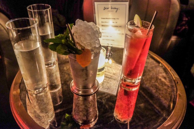 Two cocktails on a mirrored table at Bathtub Gin, one julep overflowing with ice